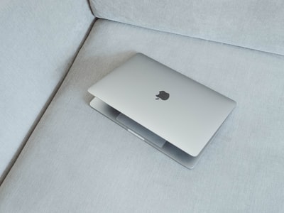 白色织物沙发上的银色MacBook